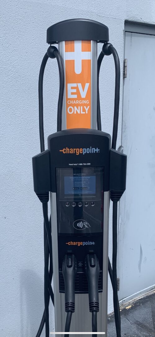 A black and orange electric car charger on the side of a building.