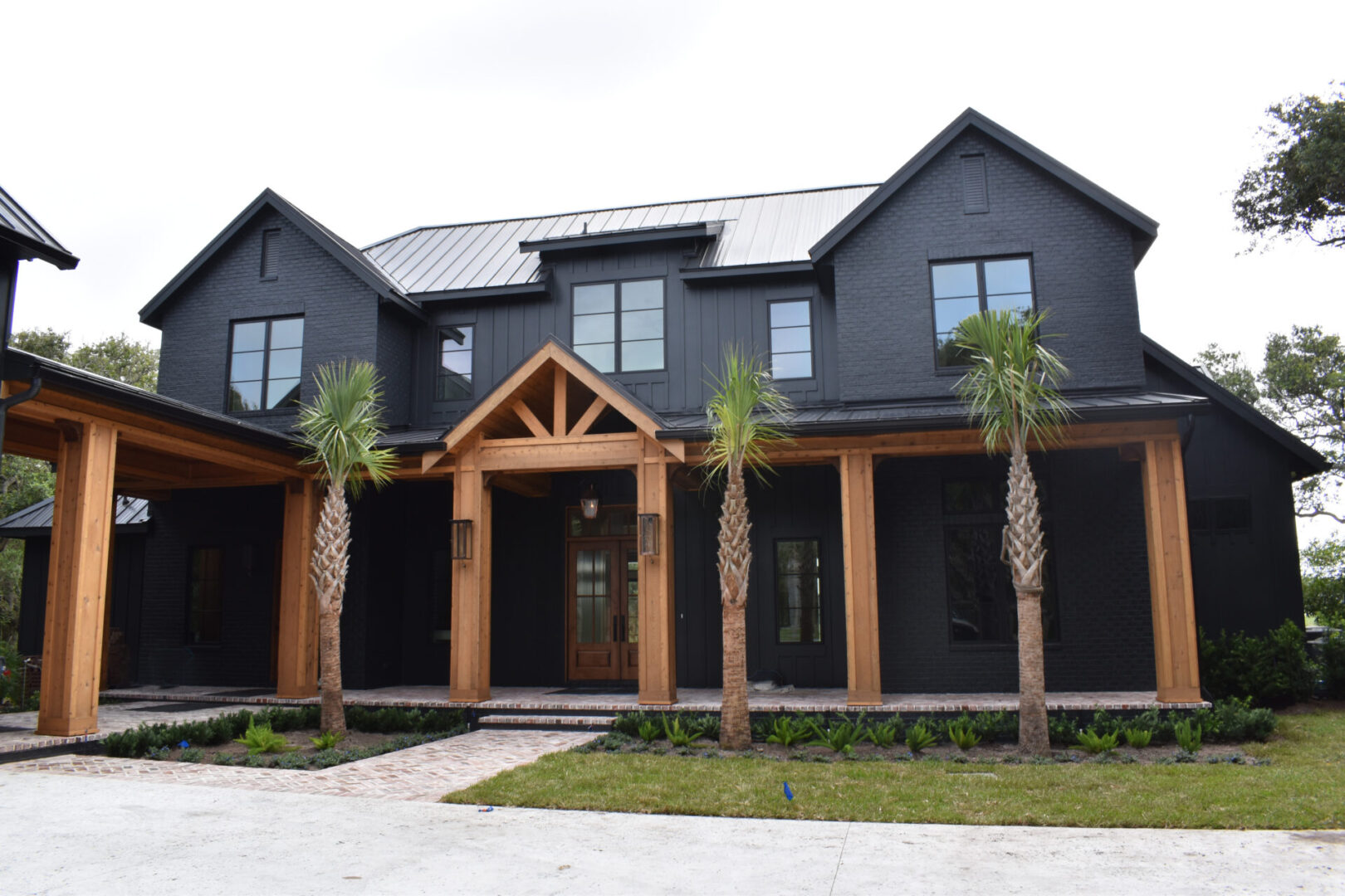 A large black house with palm trees in front of it.