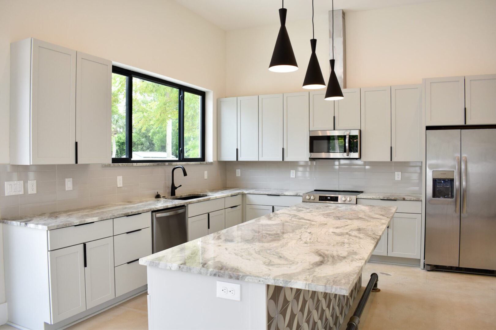 A kitchen with white cabinets and marble counter tops.